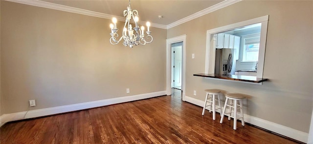 unfurnished dining area with ornamental molding, an inviting chandelier, wood finished floors, and baseboards