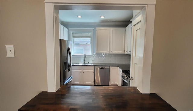 kitchen with dark countertops, white cabinetry, appliances with stainless steel finishes, and a sink