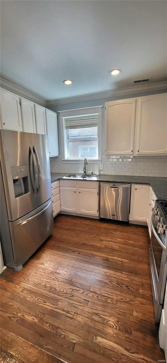 kitchen featuring stainless steel appliances, white cabinets, a sink, and dark wood-style floors