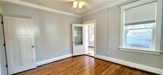 unfurnished bedroom featuring wood finished floors, visible vents, baseboards, multiple windows, and crown molding