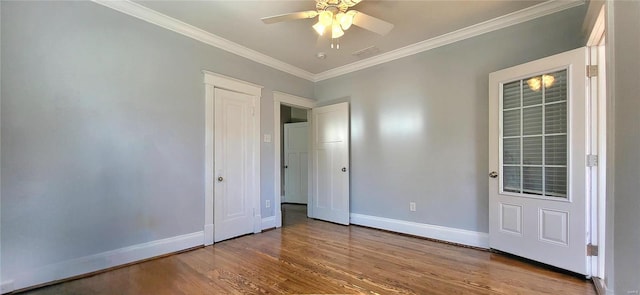 interior space featuring wood finished floors, visible vents, baseboards, a ceiling fan, and crown molding