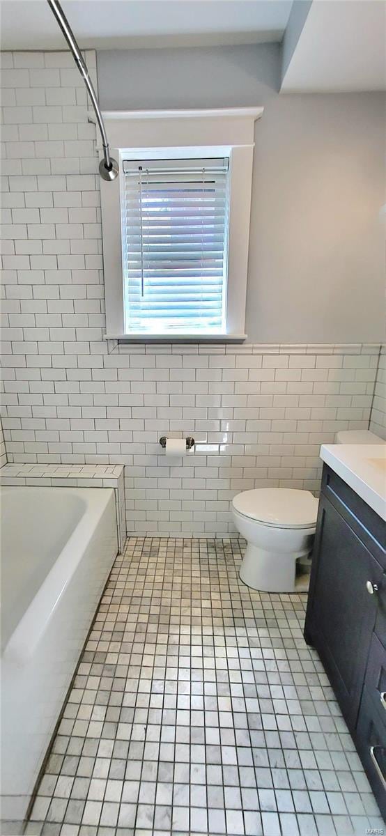 full bath featuring a wainscoted wall, tile walls, toilet, vanity, and tile patterned floors