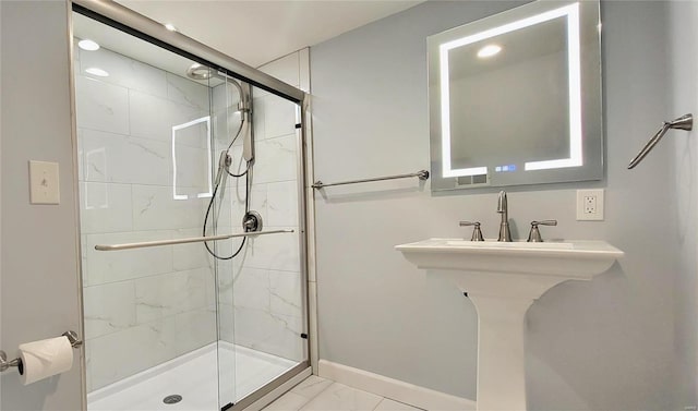 full bathroom with marble finish floor, a shower stall, and baseboards