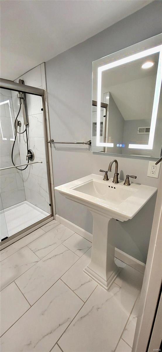 full bathroom featuring marble finish floor, a shower stall, and baseboards