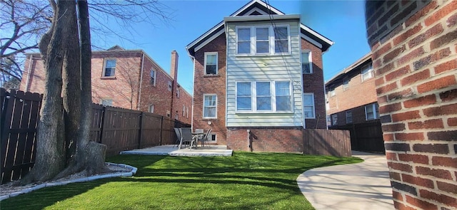 back of property with a yard, a fenced backyard, a patio, and brick siding