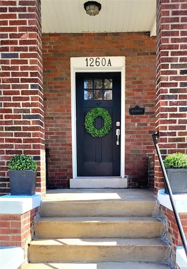 entrance to property featuring brick siding