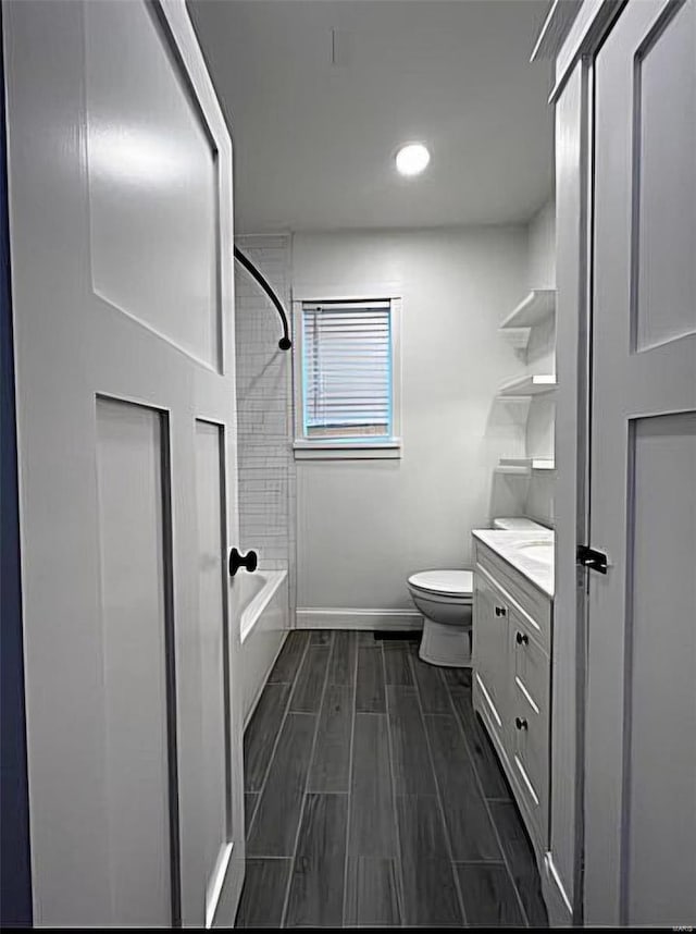 bathroom featuring baseboards, toilet, tub / shower combination, vanity, and wood finish floors