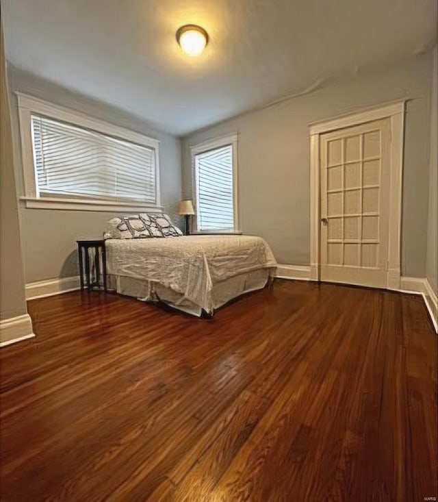 unfurnished bedroom with dark wood finished floors and baseboards