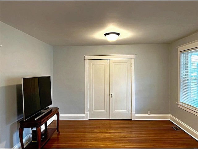 bedroom with dark wood-style floors, baseboards, visible vents, and a closet