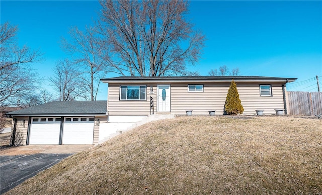 ranch-style home with driveway, an attached garage, fence, and a front yard