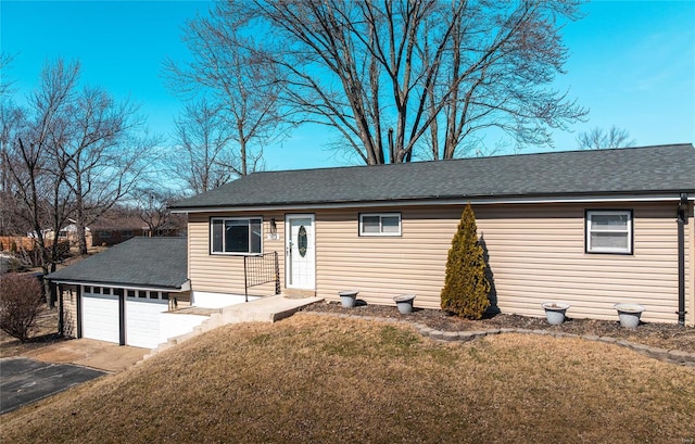 single story home featuring a garage, driveway, a shingled roof, and a front lawn