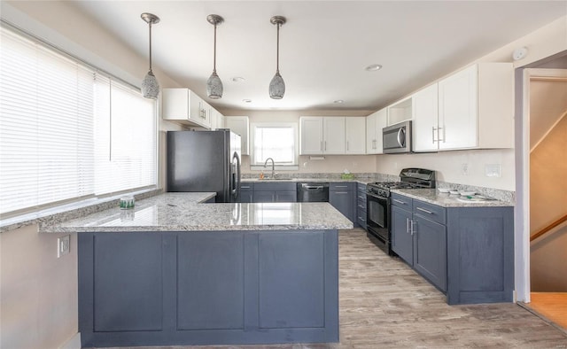 kitchen featuring white cabinets, a peninsula, light stone countertops, black appliances, and a sink