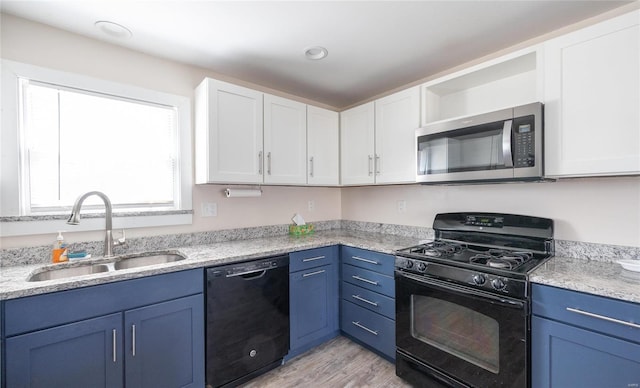 kitchen with black appliances, light wood-style floors, a sink, and white cabinets