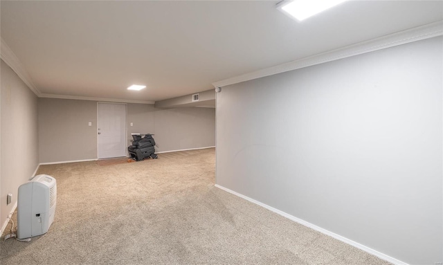 finished below grade area featuring carpet floors, visible vents, crown molding, and baseboards