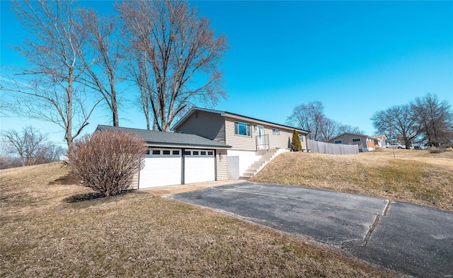 view of front of house featuring a garage, aphalt driveway, stairs, fence, and a front lawn