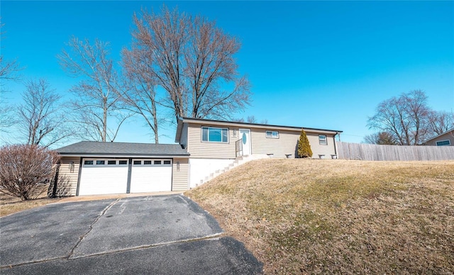 single story home with a garage, a front lawn, fence, and aphalt driveway