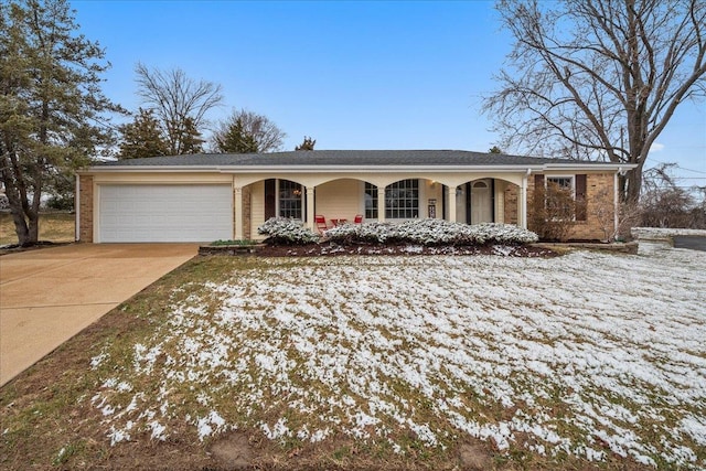 ranch-style house featuring driveway, covered porch, a garage, and brick siding