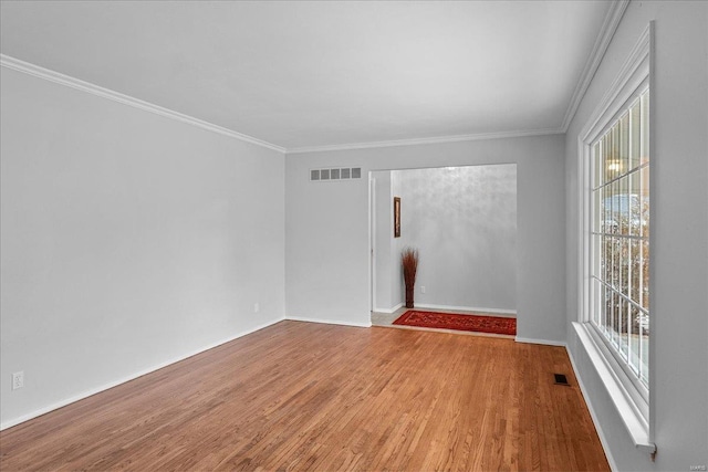 empty room featuring ornamental molding, visible vents, and wood finished floors