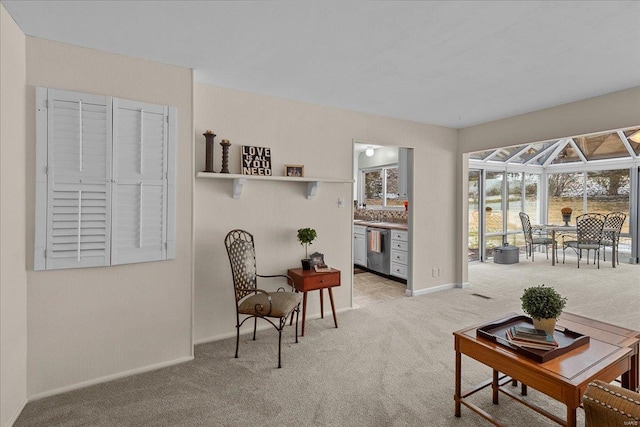 living area with a sunroom, light carpet, and baseboards