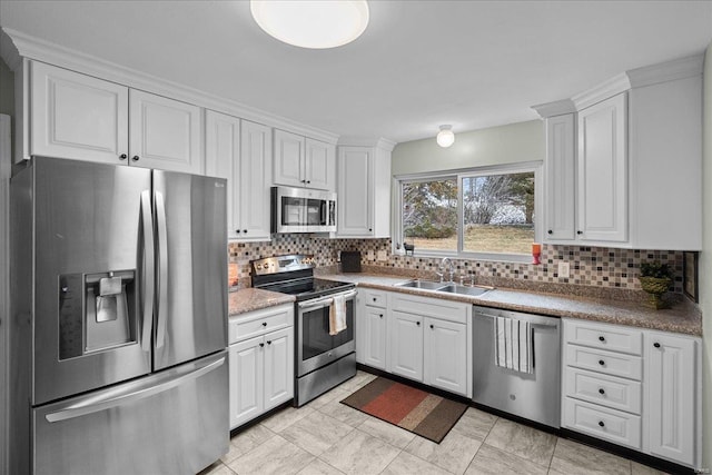 kitchen with appliances with stainless steel finishes, a sink, white cabinetry, and tasteful backsplash