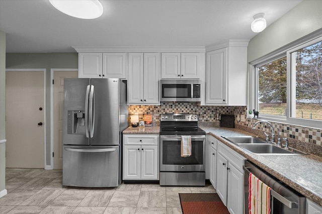 kitchen with stainless steel appliances, a sink, white cabinetry, and decorative backsplash