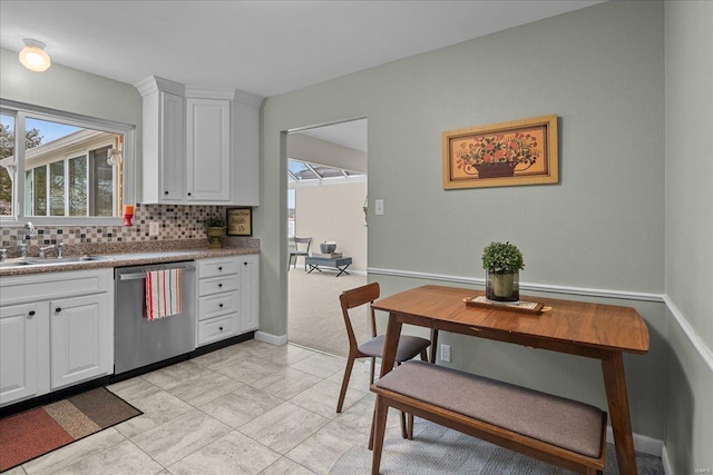 kitchen featuring white cabinetry, a sink, backsplash, and stainless steel dishwasher