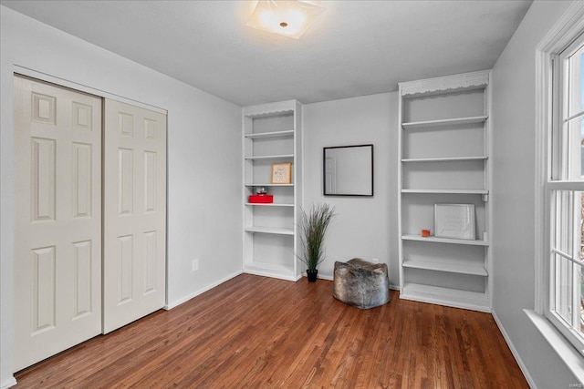 unfurnished bedroom with a closet, baseboards, and wood finished floors