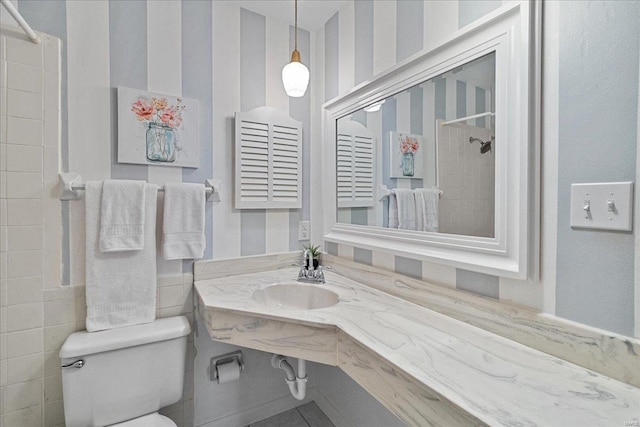 full bathroom featuring toilet, a tile shower, and a sink