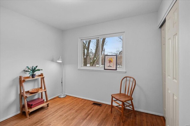 living area with visible vents, baseboards, and wood finished floors