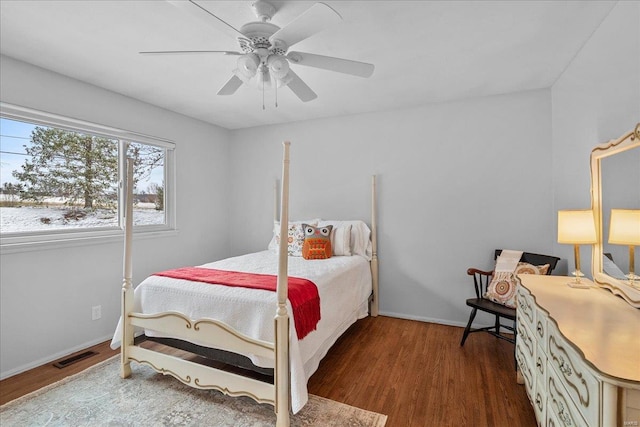 bedroom with baseboards, ceiling fan, visible vents, and wood finished floors