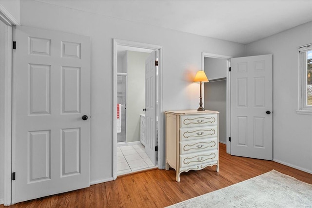 bedroom with ensuite bath, baseboards, and wood finished floors