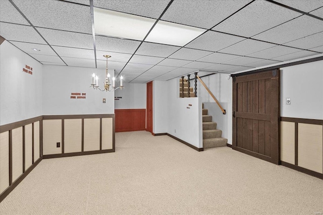 finished below grade area with carpet floors, a paneled ceiling, a wainscoted wall, and stairway