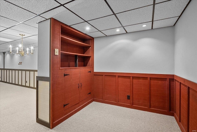 interior space featuring a chandelier, built in shelves, recessed lighting, a wainscoted wall, and light carpet