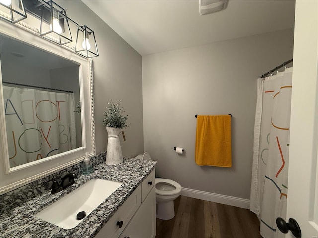 full bathroom with baseboards, toilet, wood finished floors, and vanity