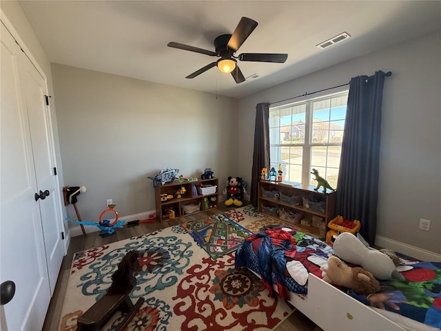 bedroom with visible vents, ceiling fan, baseboards, wood finished floors, and a closet