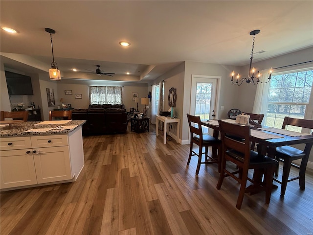 dining space featuring a wealth of natural light, a raised ceiling, wood finished floors, and recessed lighting