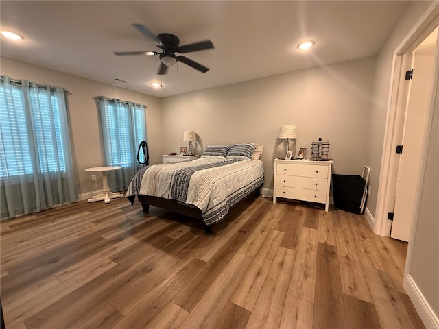 bedroom with ceiling fan, visible vents, baseboards, and wood finished floors