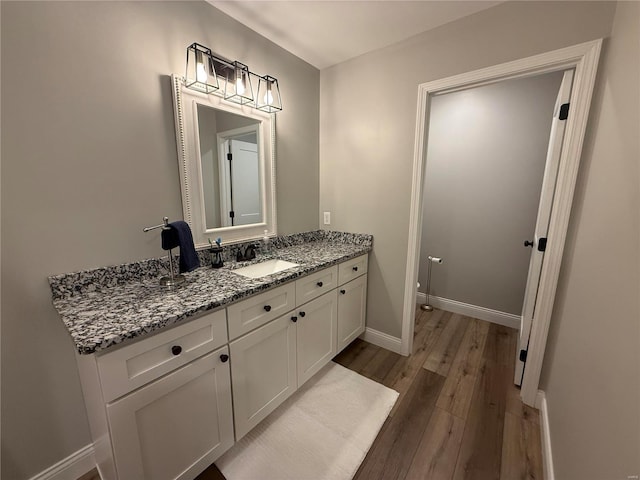 bathroom with vanity, wood finished floors, and baseboards