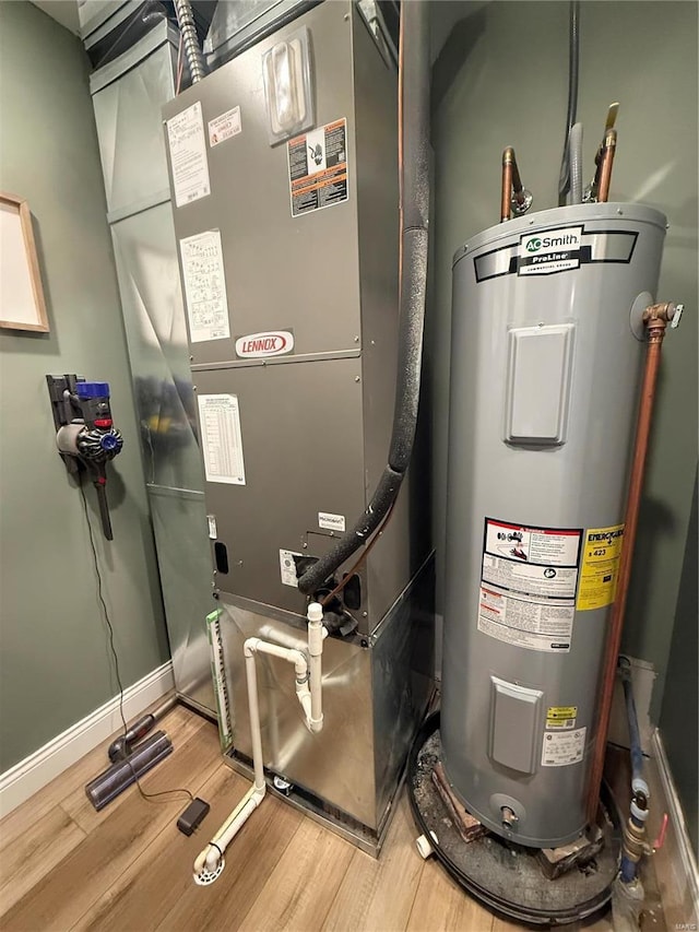 utility room featuring heating unit and electric water heater