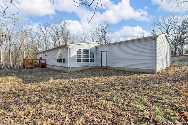 back of property with a yard and a wooden deck