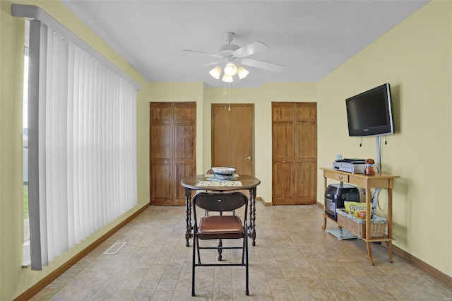 interior space with baseboards, visible vents, and a ceiling fan