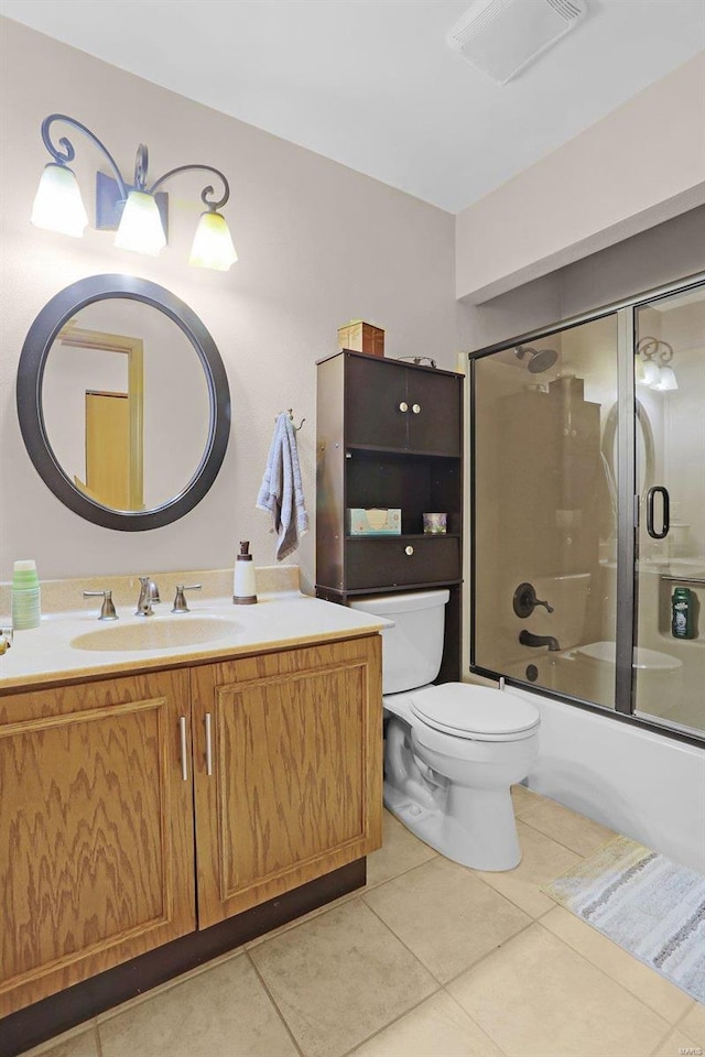 full bath featuring combined bath / shower with glass door, vanity, toilet, and tile patterned floors