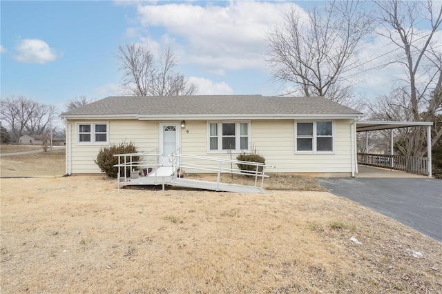 ranch-style home with driveway, an attached carport, and roof with shingles