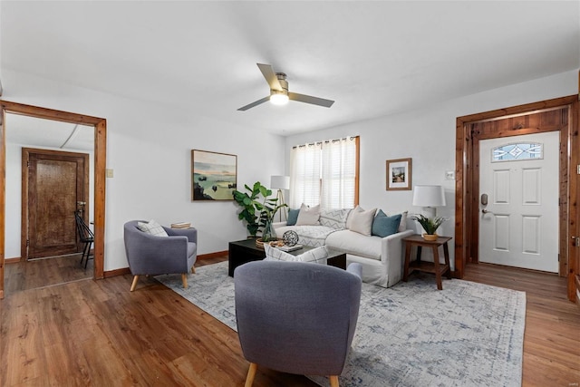 living area featuring baseboards, a ceiling fan, and wood finished floors