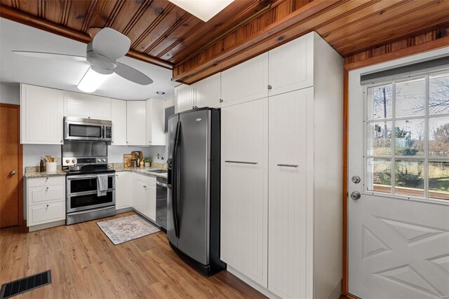 kitchen featuring light stone counters, stainless steel appliances, visible vents, light wood-style flooring, and white cabinetry