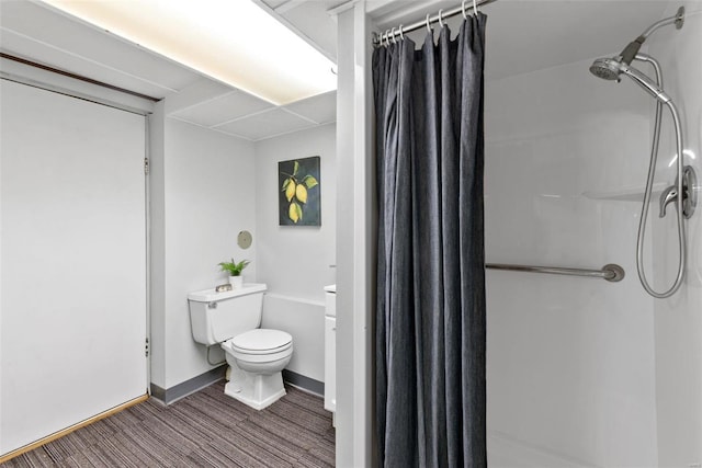 bathroom featuring toilet, baseboards, wood finished floors, and a shower with shower curtain