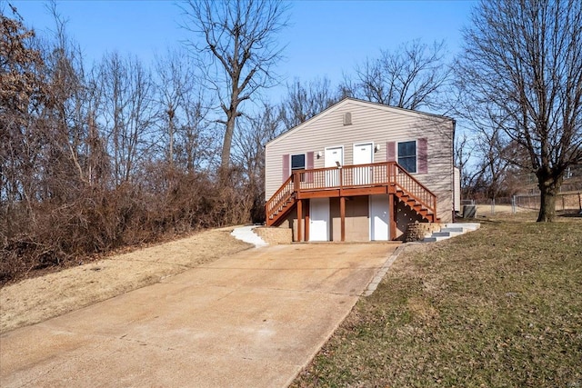 view of front of house featuring a front yard, concrete driveway, an attached garage, and stairs