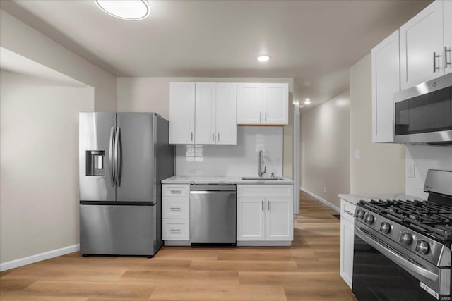 kitchen featuring appliances with stainless steel finishes, light wood-type flooring, light countertops, and a sink