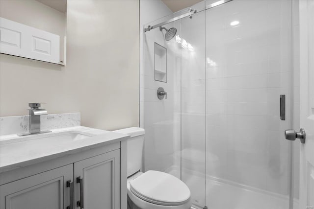 bathroom featuring toilet, a stall shower, and vanity