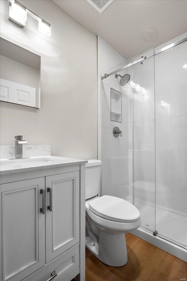 full bath with visible vents, toilet, wood finished floors, vanity, and a shower stall